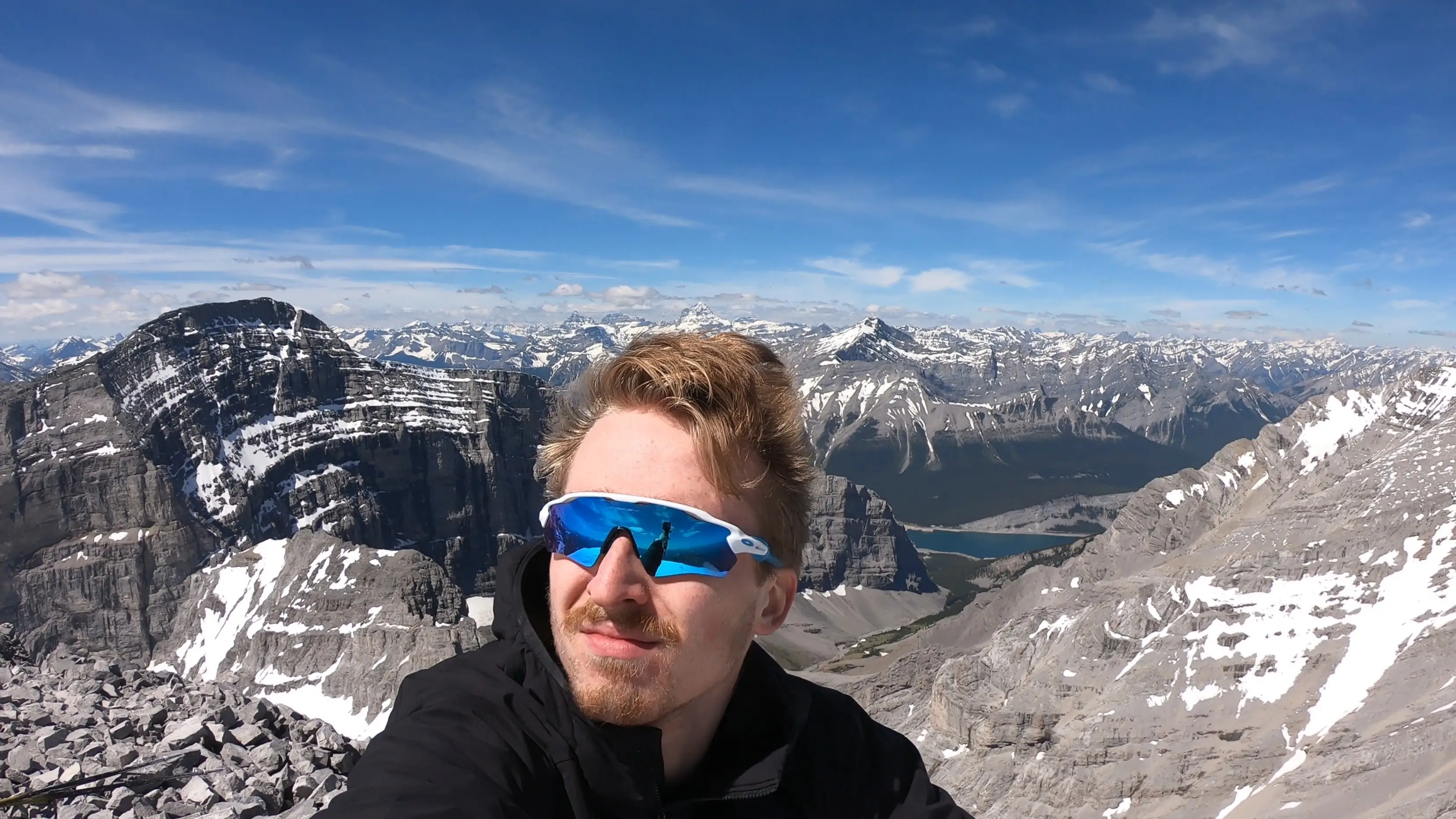 Summit photo from Wind Mountain featuring Haldan Borglum with sweeping views of the Canadian Rockies and the Spray Valley far below.