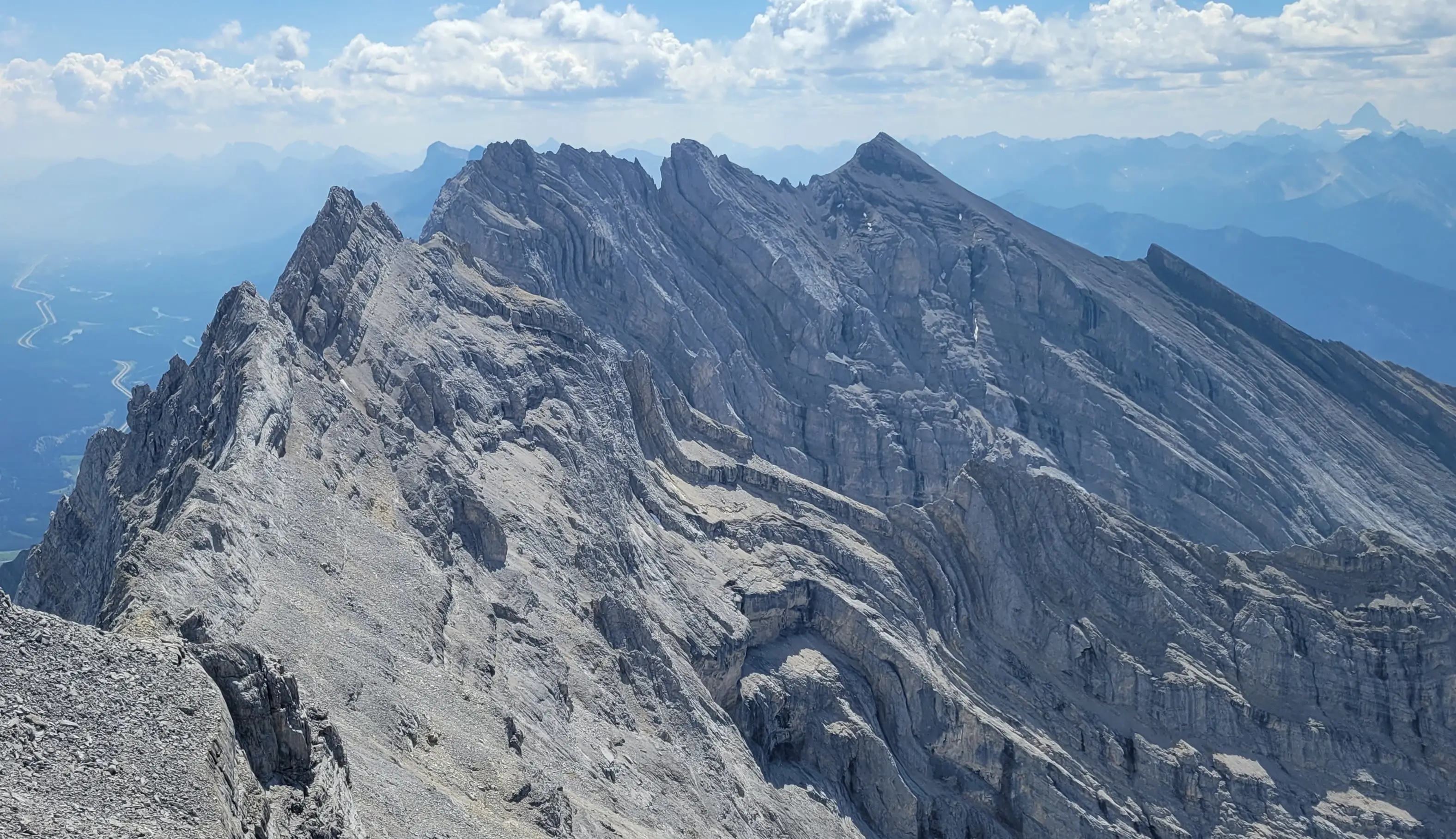 Looking along the rugged ridgeline of Cascade Mountain during the Cascade Traverse, with the distinct banded limestone layers of the northeast face and the Bow Valley far below.