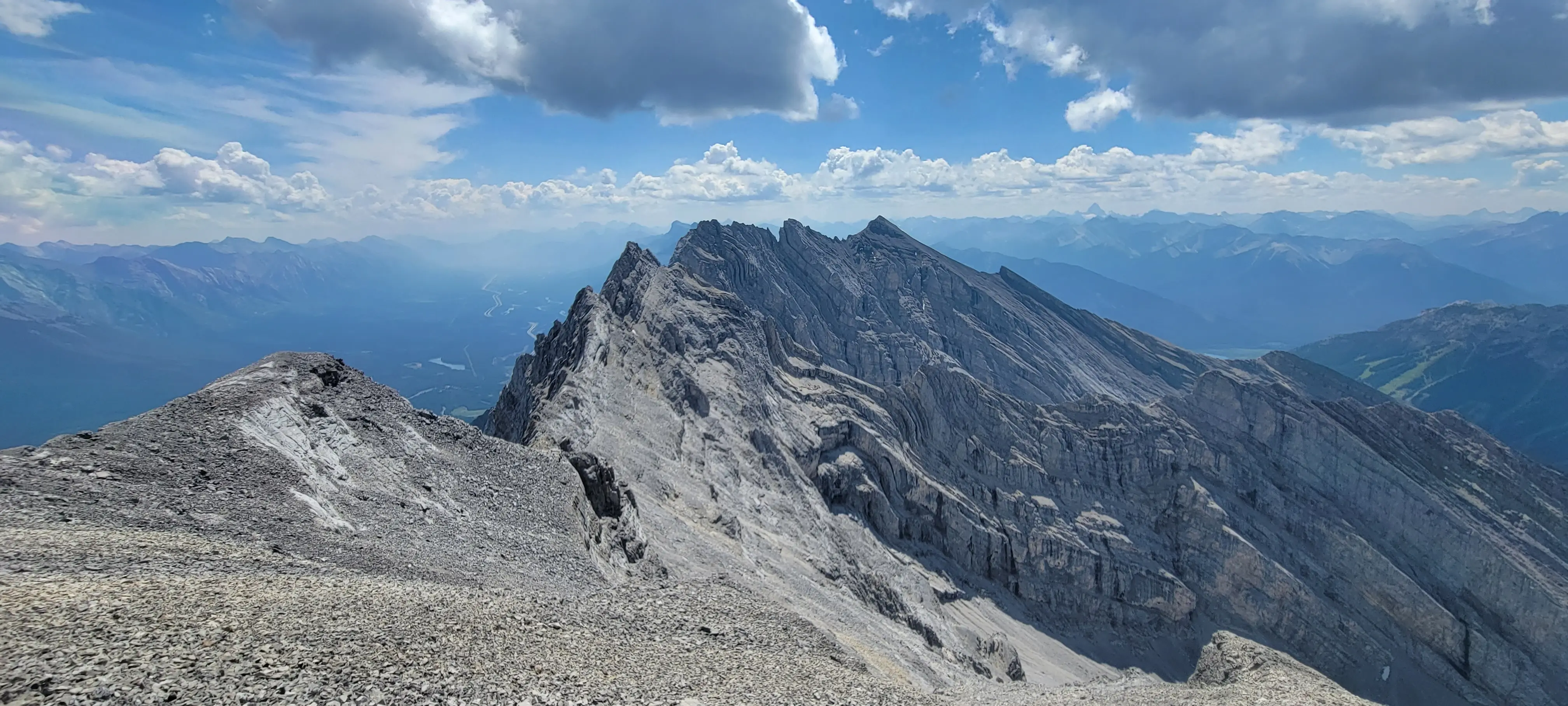 Looking along the rugged ridgeline of Cascade Mountain during the Cascade Traverse, with the distinct banded limestone layers of the northeast face and the Bow Valley far below.