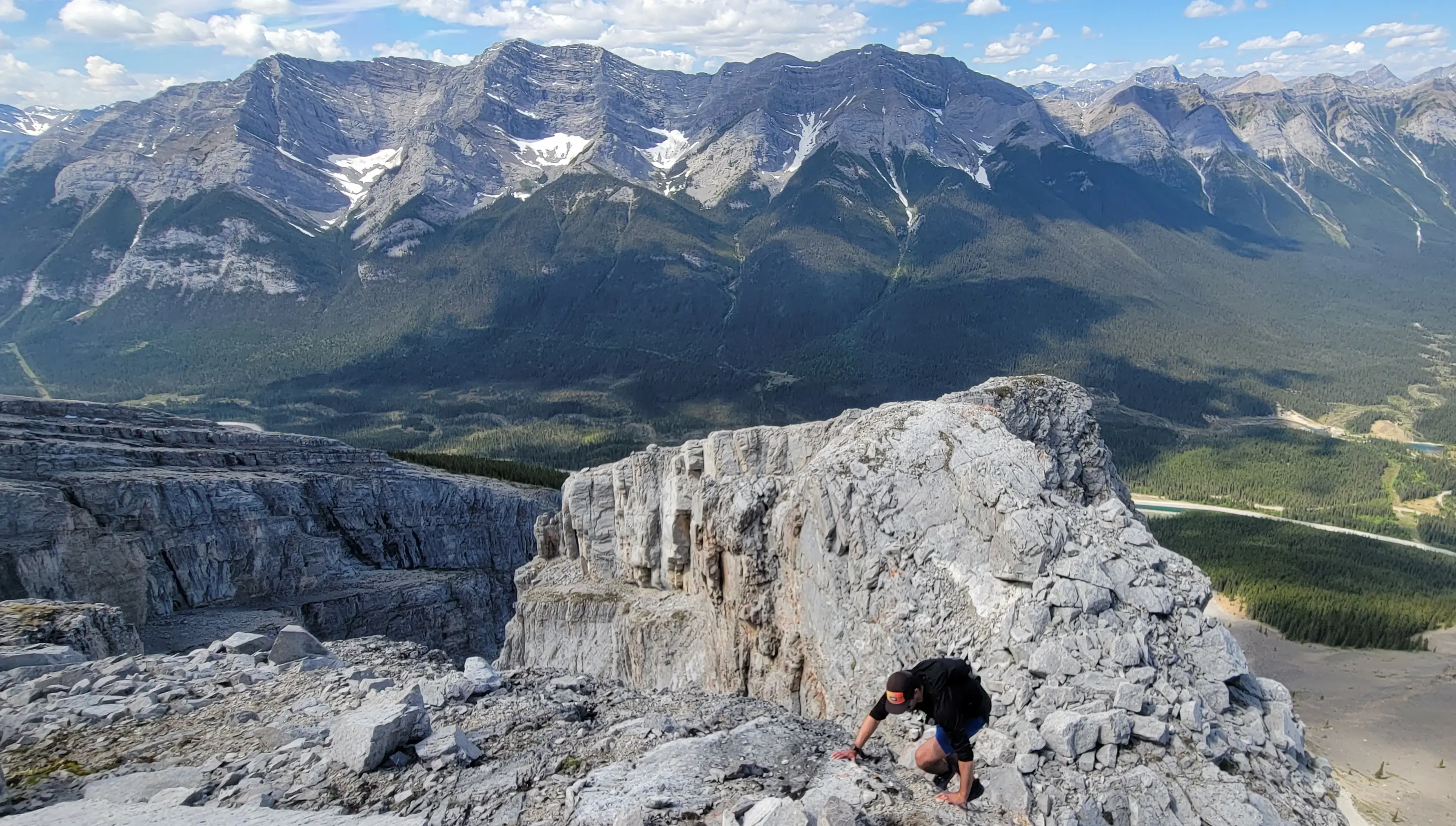 A climber reaching the top of the amphitheater that can be used to link up Miner's Peak and Mount Lawrence Grassi with views of the Goatview massif behind.