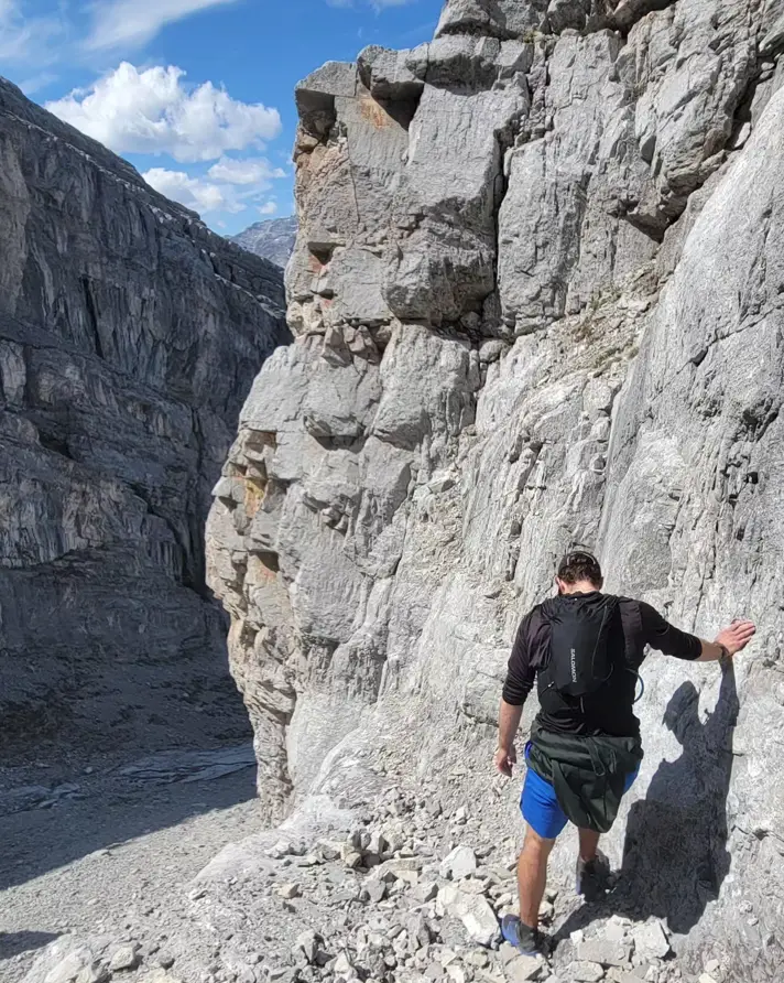 A climber at the base of a steep climb on Mount Lawrence Grassi during a traverse of the Ehagay Nakoda massif.
