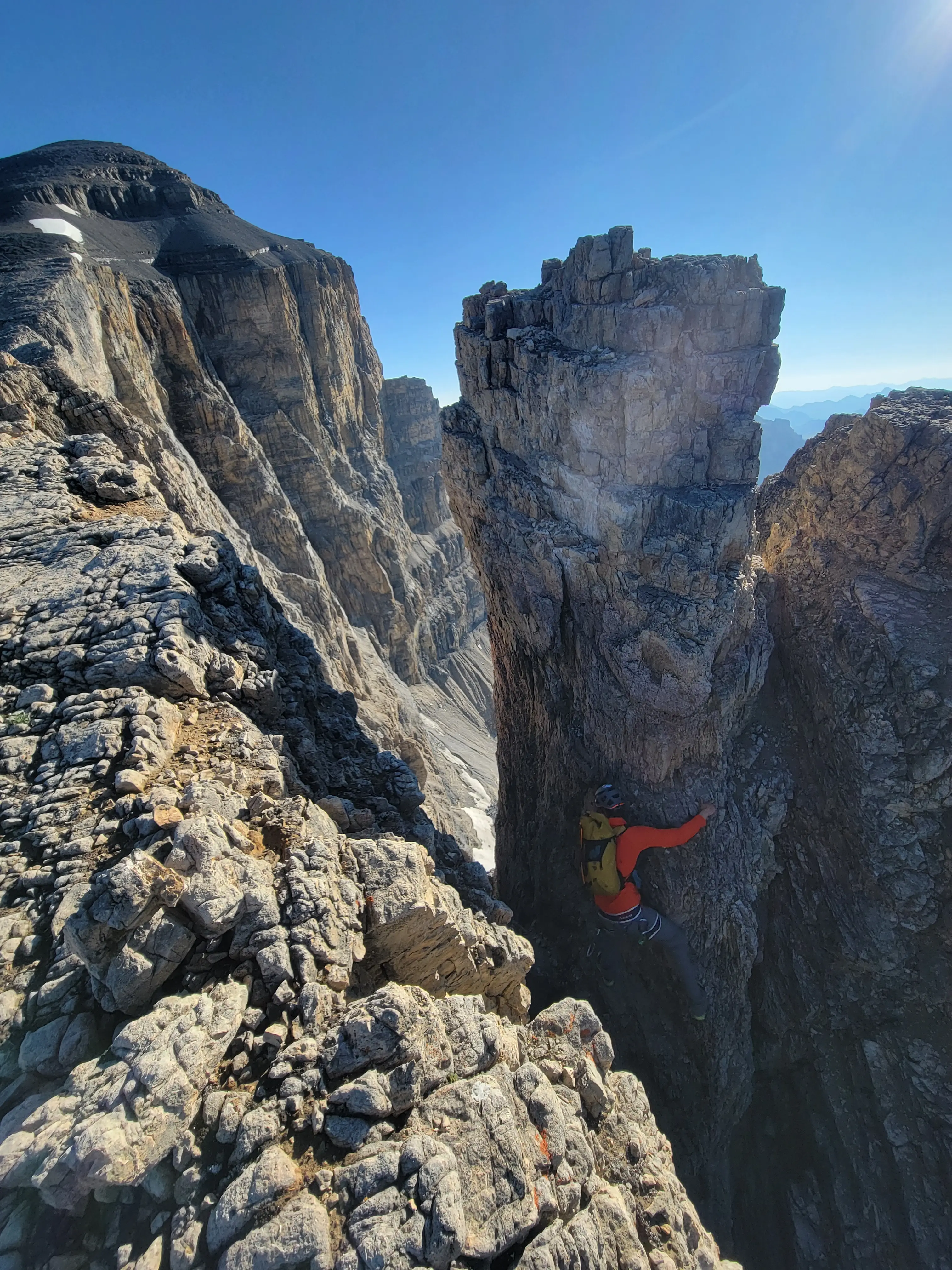 Climber free-soloing the first notch on Mount Cline with towering limestone cliffs and expansive alpine backdrop in the Canadian Rockies