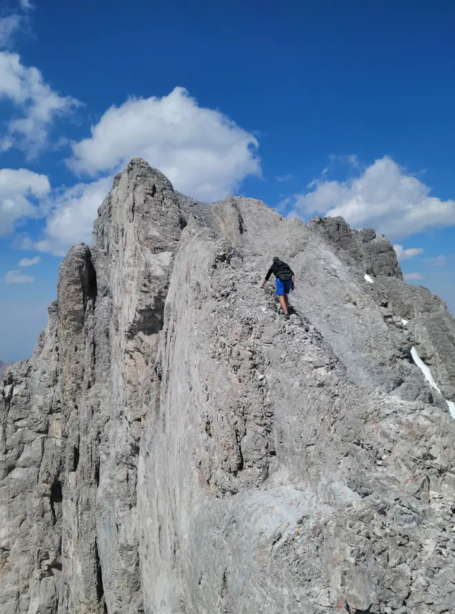 A climber ascending the exceedingly exposed ridge of Mount French nicknamed The Guillotine.