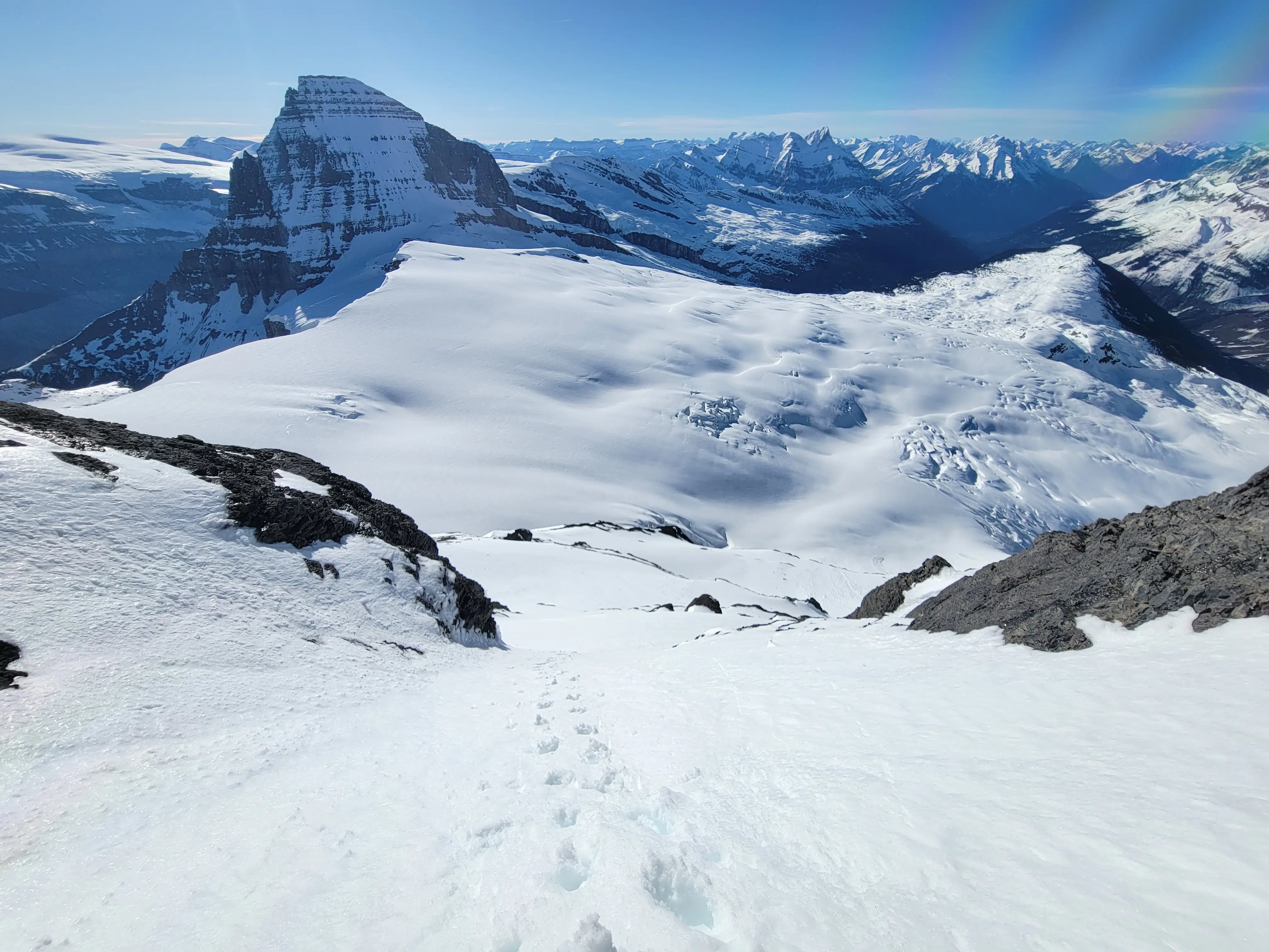 View looking down the steep south face snow climb on Mount King Edward, with Mount Columbia rising prominently to the left and the Bush River valley stretching into the distance.