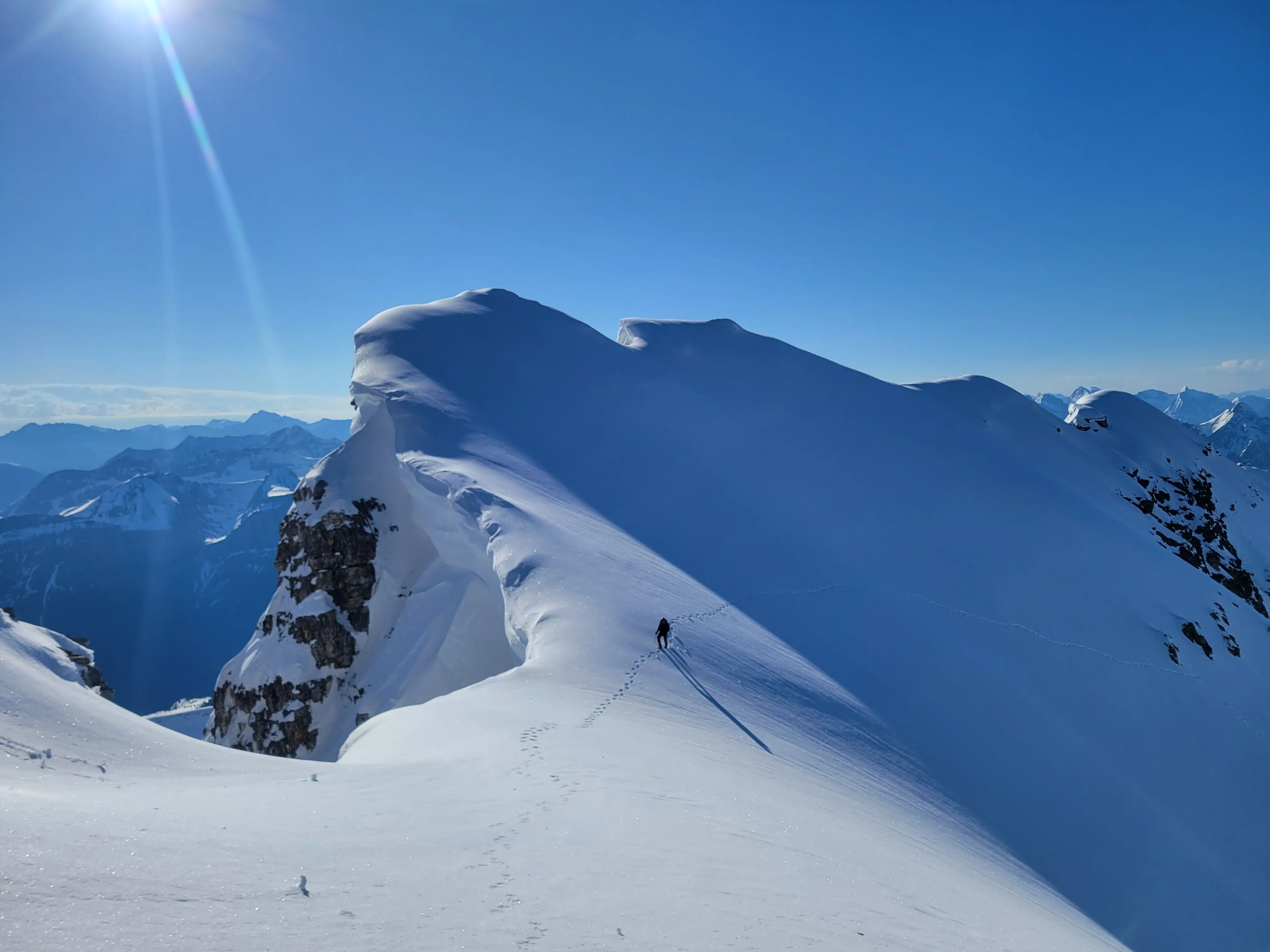 A climber on the upper flanks of Mount King George with massive cornices a bit too close for comfort.