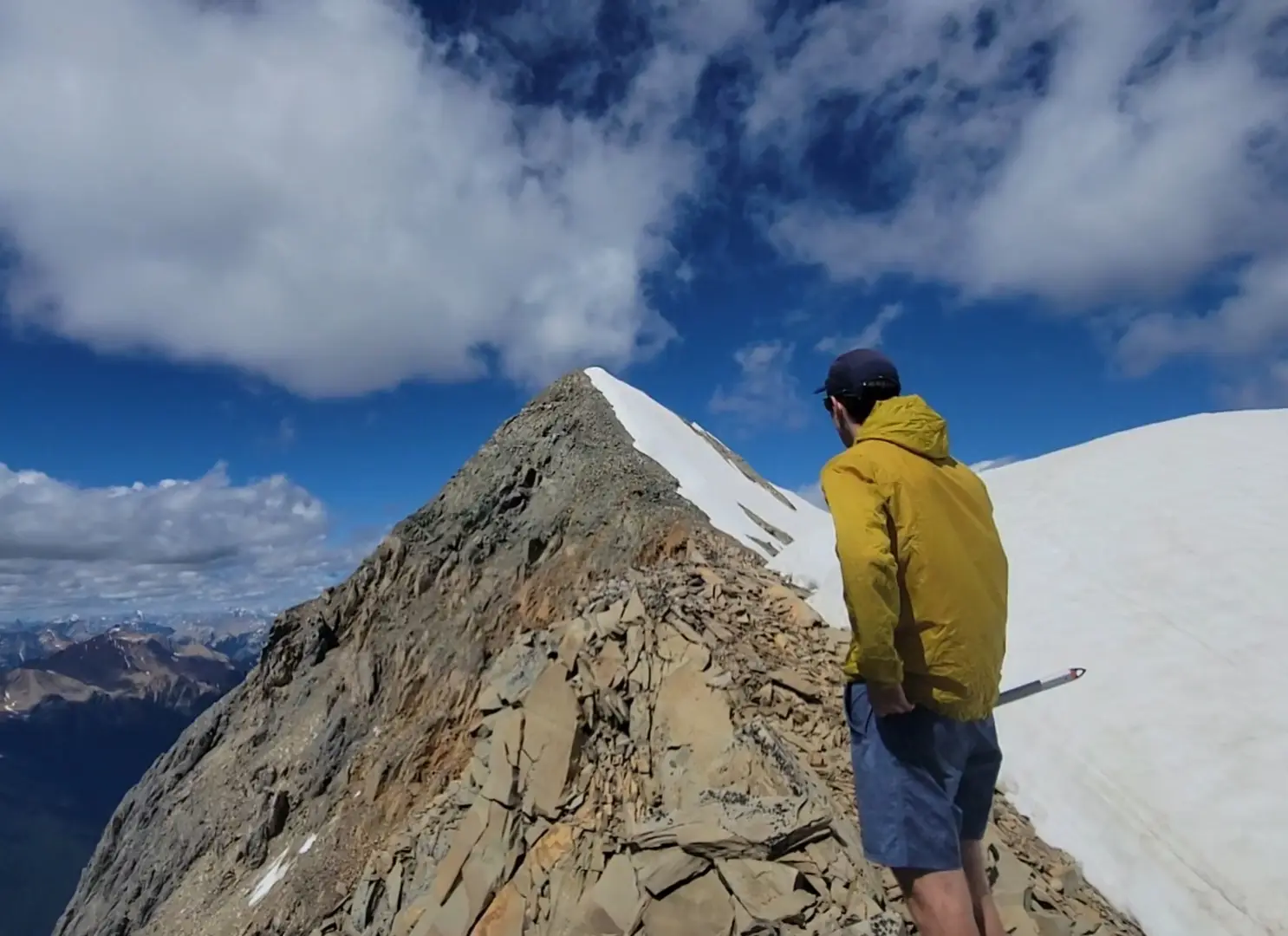 A climber on the south ridge of Mount Vaux with snow on it's east side and a sizable drop to the west.