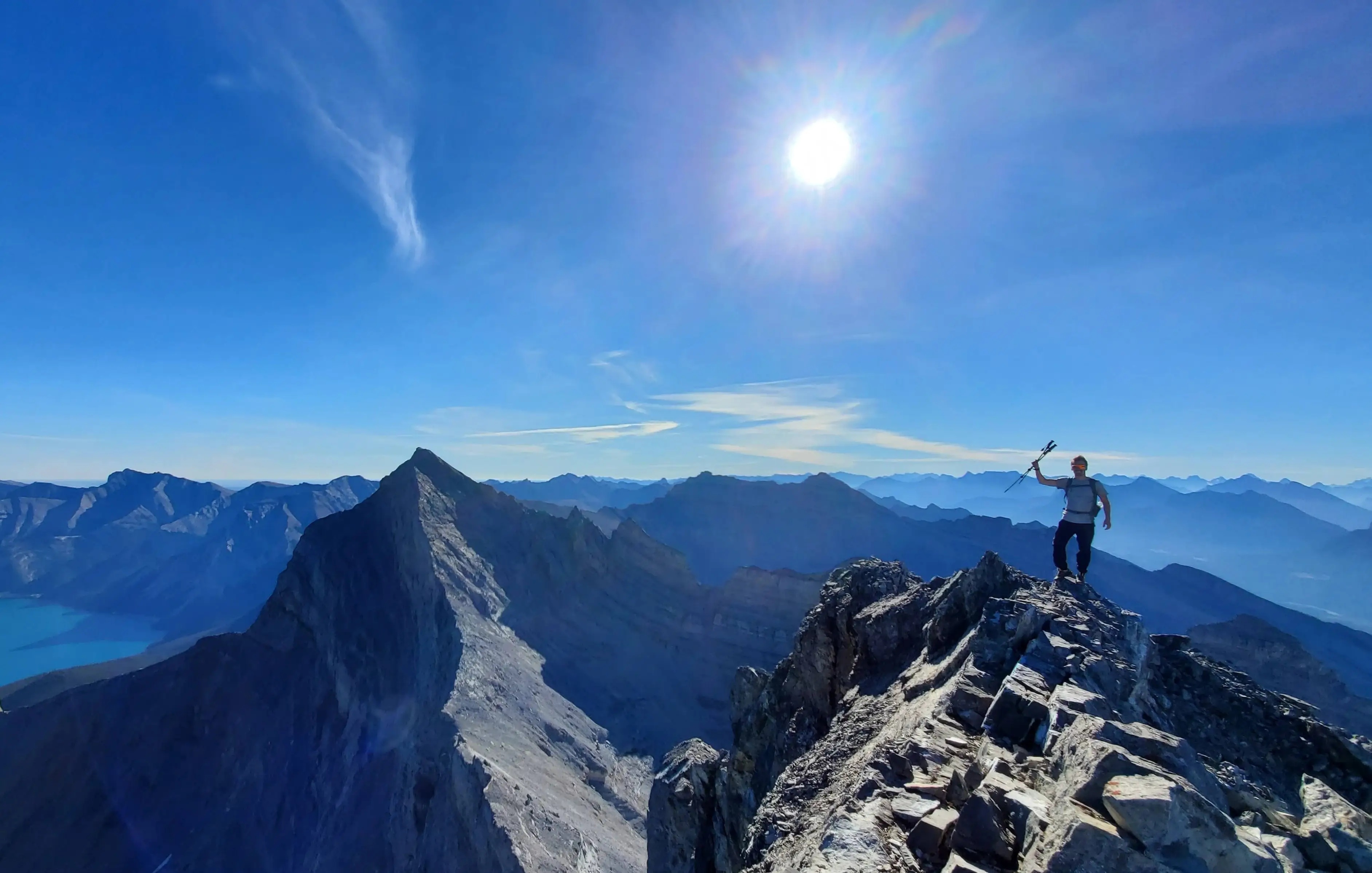 Summit photo from the top of Mount Inglismaldie with Mount Girouard and Mount Peechee in the background on a blue sky day.